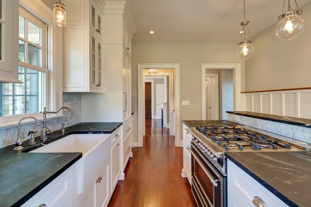 Example of an ornate single-wall dark wood floor kitchen design in New York with a farmhouse sink, soapstone countertops and an island