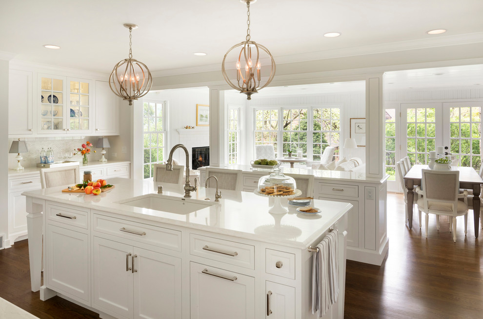 Example of a large classic medium tone wood floor open concept kitchen design in Minneapolis with an undermount sink, shaker cabinets, white cabinets, two islands and white countertops