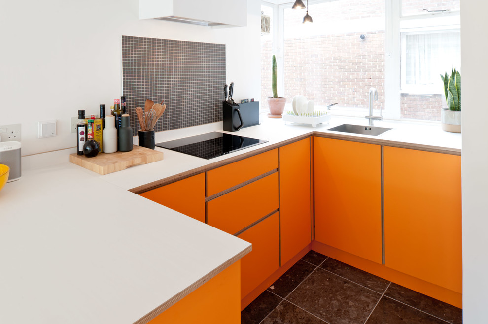 На фото: маленькая отдельная, п-образная кухня в современном стиле с плоскими фасадами, оранжевыми фасадами, серым фартуком, фартуком из плитки мозаики и черным полом для на участке и в саду с