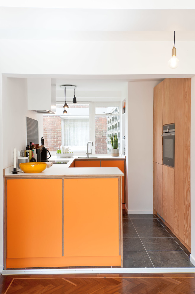 Idéer för avskilda, små funkis u-kök, med en undermonterad diskho, släta luckor, orange skåp, laminatbänkskiva, grått stänkskydd, rostfria vitvaror och svart golv