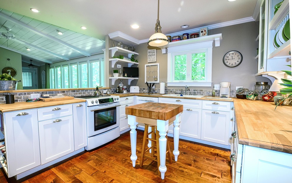 Foto de cocina tradicional abierta con armarios estilo shaker, puertas de armario blancas, encimera de madera, salpicadero marrón, salpicadero de azulejos de piedra y electrodomésticos blancos
