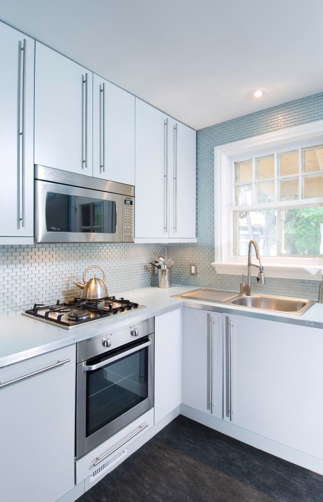 Inspiration for a small contemporary l-shaped kitchen in Ottawa with a built-in sink, flat-panel cabinets, white cabinets, blue splashback, metal splashback, stainless steel appliances and black floors.