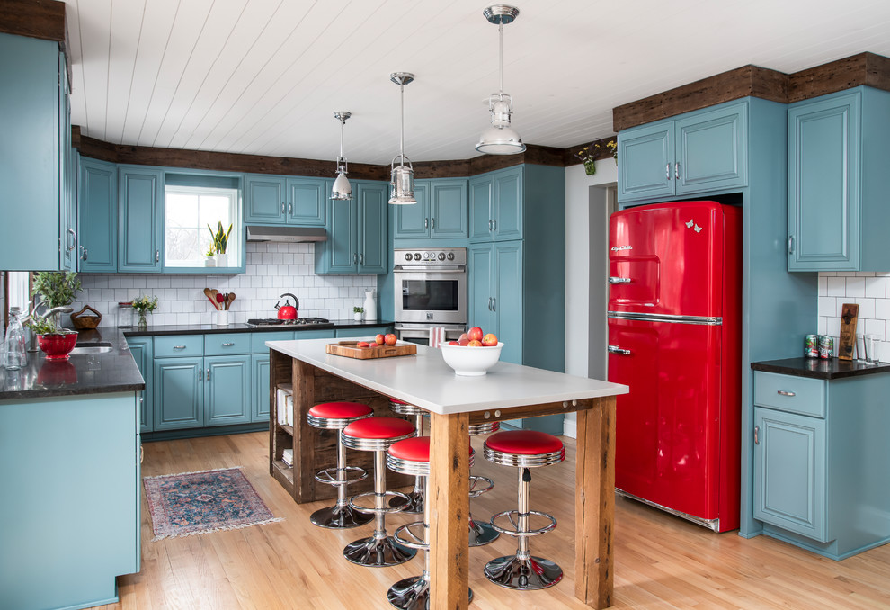 Inspiration for a mid-sized eclectic u-shaped light wood floor open concept kitchen remodel in Chicago with an undermount sink, raised-panel cabinets, blue cabinets, quartz countertops, white backsplash, ceramic backsplash, colored appliances, an island and gray countertops