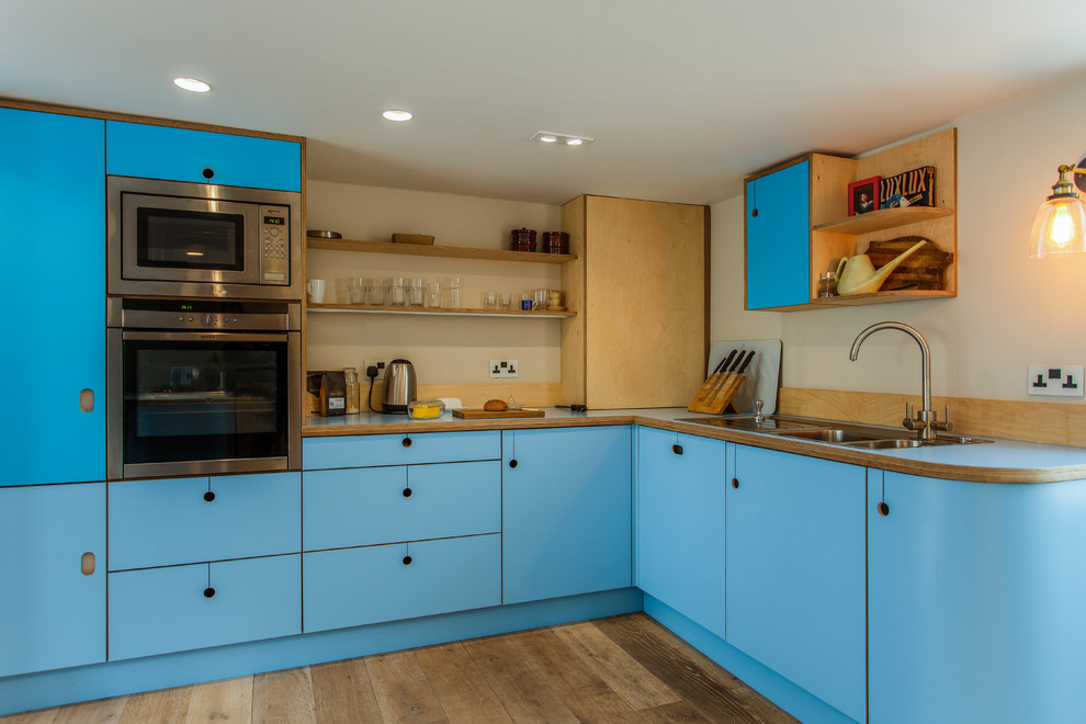 Inspiration for a medium sized bohemian l-shaped kitchen/diner in Sussex with flat-panel cabinets, turquoise cabinets, laminate countertops, a breakfast bar and blue worktops.