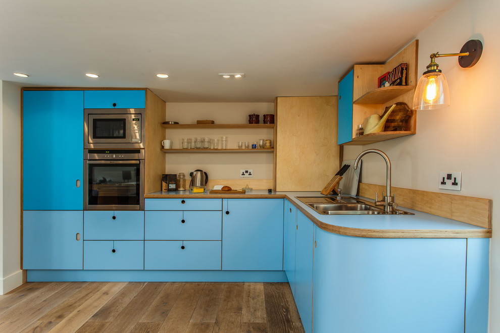 Источник вдохновения для домашнего уюта: угловая кухня среднего размера в стиле фьюжн с обеденным столом, плоскими фасадами, бирюзовыми фасадами, столешницей из ламината, полуостровом и синей столешницей