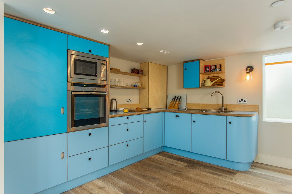 На фото: угловая кухня среднего размера в стиле фьюжн с обеденным столом, плоскими фасадами, бирюзовыми фасадами, столешницей из ламината, полуостровом и синей столешницей