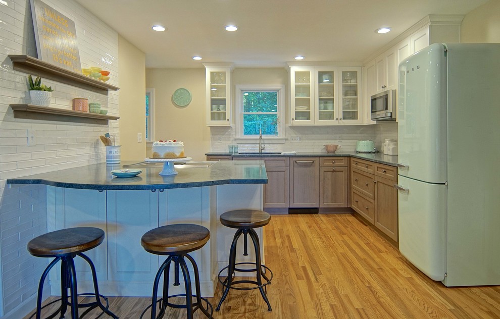 Small elegant l-shaped medium tone wood floor kitchen photo in Boston with an undermount sink, glass-front cabinets, white cabinets, soapstone countertops, white backsplash, subway tile backsplash and colored appliances