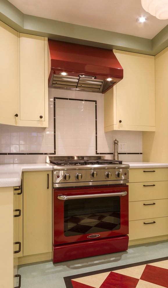トロントにある小さなミッドセンチュリースタイルのおしゃれなキッチン (一体型シンク、フラットパネル扉のキャビネット、黄色いキャビネット、人工大理石カウンター、白いキッチンパネル、セラミックタイルのキッチンパネル、カラー調理設備、アイランドなし) の写真