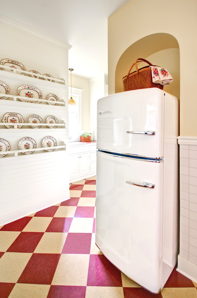 Modelo de cocina tradicional cerrada con armarios con paneles con relieve, puertas de armario blancas, salpicadero blanco, electrodomésticos blancos y suelo multicolor