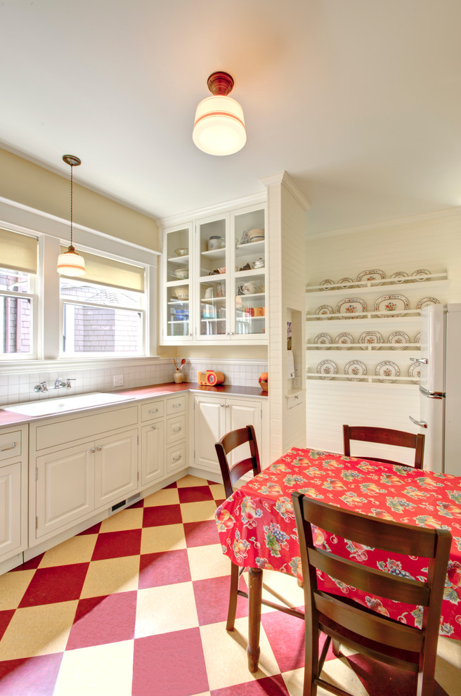Example of a classic kitchen design in Portland with a drop-in sink, glass-front cabinets, white cabinets, laminate countertops and white appliances