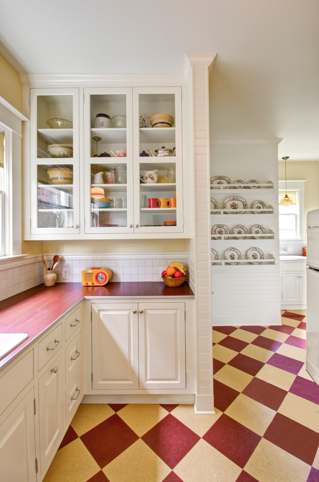 Photo of a classic kitchen in Portland with raised-panel cabinets, white cabinets, laminate countertops, white splashback, white appliances and multi-coloured floors.