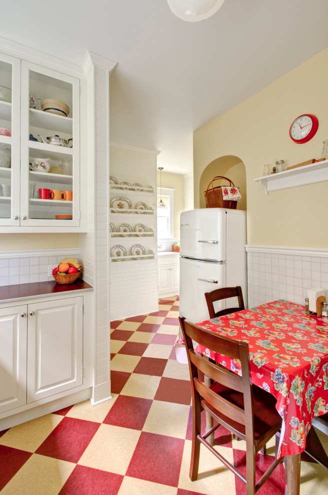 Eat-in kitchen - traditional multicolored floor eat-in kitchen idea in Portland with raised-panel cabinets, white cabinets, laminate countertops, white backsplash, white appliances and red countertops