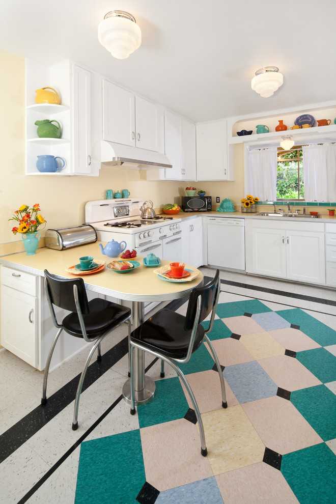 Inspiration for a mid-sized mid-century modern u-shaped linoleum floor and multicolored floor kitchen remodel in Santa Barbara with white cabinets, laminate countertops, white appliances, shaker cabinets, a double-bowl sink, an island and white countertops