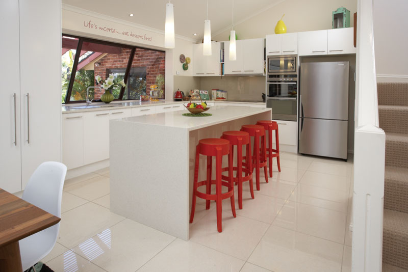 Eat-in kitchen - mid-sized mid-century modern l-shaped porcelain tile eat-in kitchen idea in Sydney with a double-bowl sink, flat-panel cabinets, white cabinets, quartz countertops, gray backsplash, glass sheet backsplash, stainless steel appliances and an island