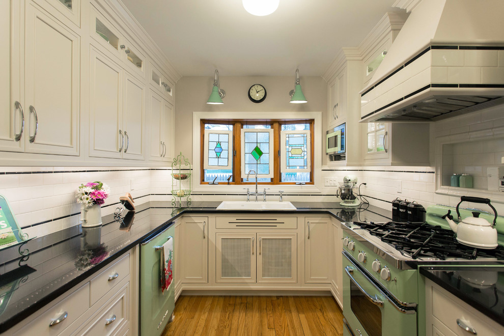 Enclosed kitchen - small 1950s u-shaped medium tone wood floor and brown floor enclosed kitchen idea in Boston with a double-bowl sink, recessed-panel cabinets, white cabinets, granite countertops, white backsplash, colored appliances, no island and ceramic backsplash