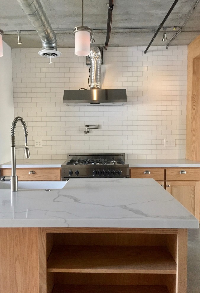 Inspiration for a small industrial single-wall concrete floor and gray floor eat-in kitchen remodel in Los Angeles with a farmhouse sink, shaker cabinets, light wood cabinets, quartzite countertops, white backsplash, subway tile backsplash, stainless steel appliances and an island