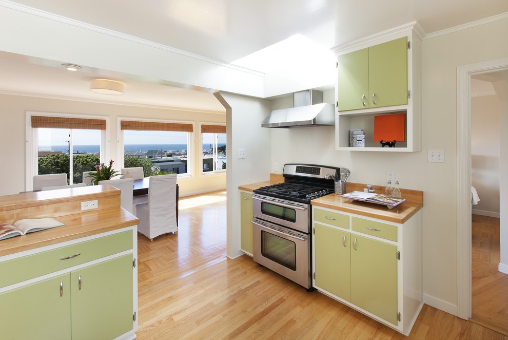 Inspiration for a traditional kitchen/diner in San Francisco with flat-panel cabinets, green cabinets, wood worktops and stainless steel appliances.