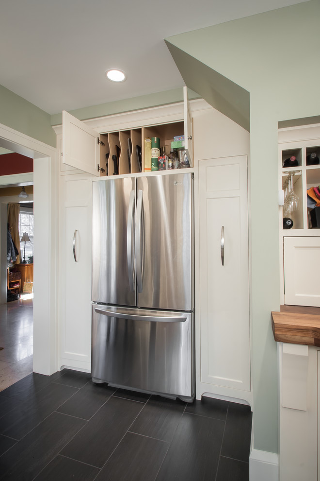 This is an example of a medium sized rural l-shaped enclosed kitchen in Minneapolis with a submerged sink, flat-panel cabinets, white cabinets, soapstone worktops, beige splashback, metro tiled splashback, stainless steel appliances and porcelain flooring.