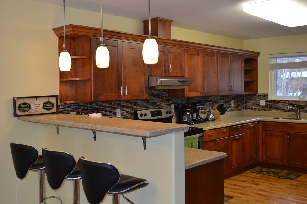 Inredning av ett modernt mellanstort kök, med en undermonterad diskho, skåp i shakerstil, skåp i mellenmörkt trä, brunt stänkskydd, stänkskydd i glaskakel, rostfria vitvaror, ljust trägolv, granitbänkskiva och en halv köksö