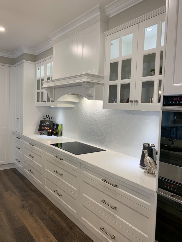 Exempel på ett mycket stort klassiskt vit vitt kök, med en undermonterad diskho, luckor med infälld panel, grå skåp, bänkskiva i kvarts, vitt stänkskydd, stänkskydd i sten, svarta vitvaror, mellanmörkt trägolv, en köksö och brunt golv