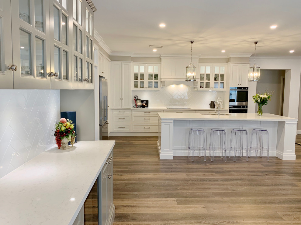 Huge transitional l-shaped medium tone wood floor and brown floor open concept kitchen photo in Sydney with an undermount sink, recessed-panel cabinets, gray cabinets, quartz countertops, white backsplash, stone slab backsplash, black appliances, an island and white countertops