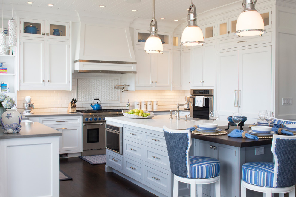 Example of a large classic dark wood floor eat-in kitchen design in New York with a farmhouse sink, white cabinets, white backsplash, subway tile backsplash, stainless steel appliances and an island