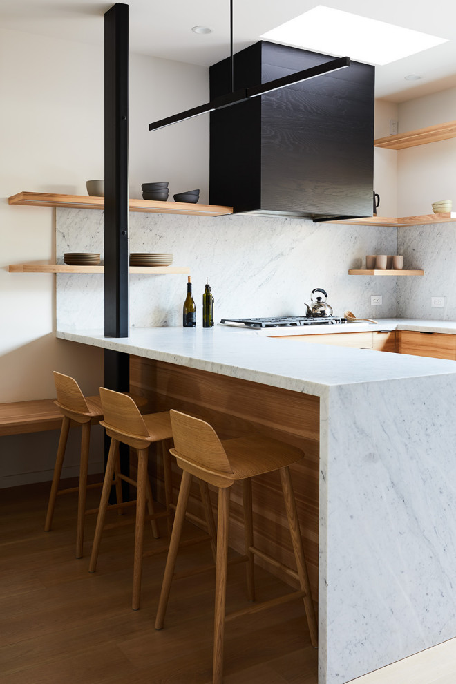 Foto på ett funkis kök och matrum, med en undermonterad diskho, släta luckor, skåp i ljust trä, marmorbänkskiva, stänkskydd i marmor, integrerade vitvaror och ljust trägolv