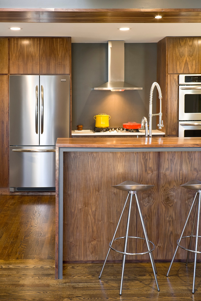 Mid-sized trendy u-shaped kitchen photo in Kansas City with flat-panel cabinets, medium tone wood cabinets, wood countertops and stainless steel appliances