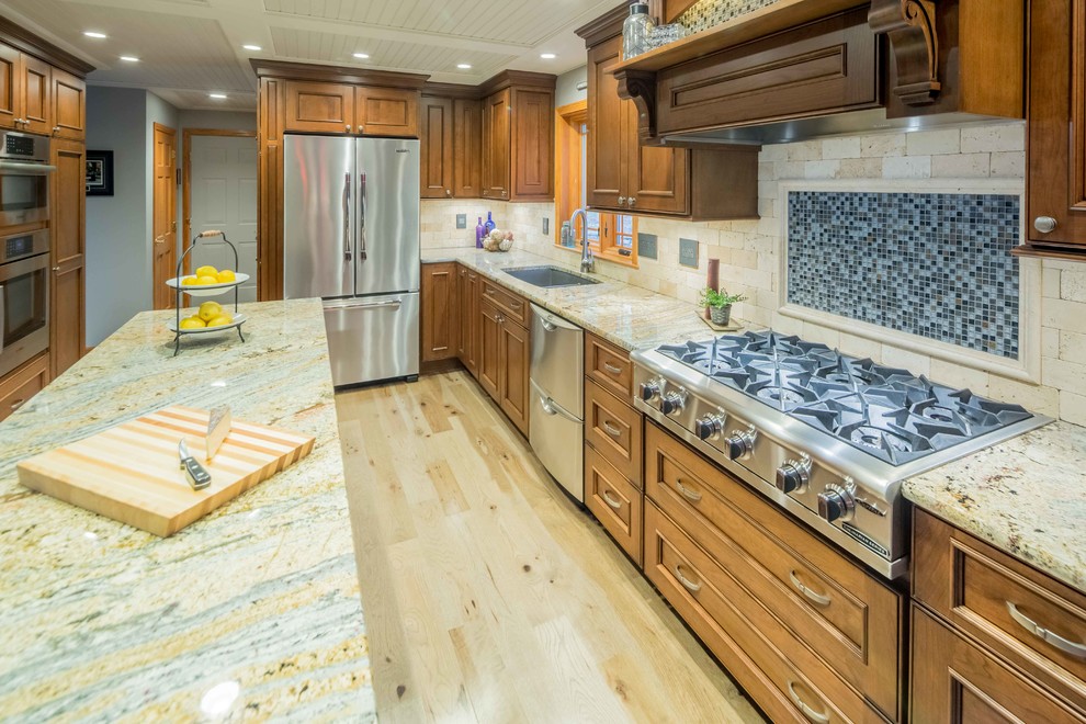 This is an example of a small classic l-shaped kitchen/diner in Boston with a submerged sink, beaded cabinets, brown cabinets, granite worktops, beige splashback, travertine splashback, stainless steel appliances, light hardwood flooring, an island and beige floors.