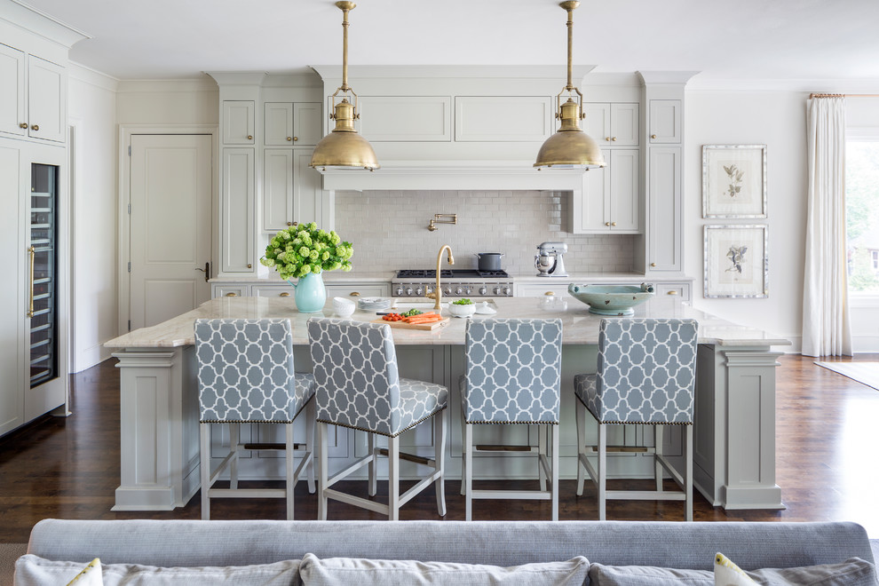 Inredning av ett klassiskt mellanstort grå grått kök, med en undermonterad diskho, luckor med infälld panel, grå skåp, bänkskiva i kvartsit, grått stänkskydd, stänkskydd i keramik, integrerade vitvaror, mörkt trägolv, en köksö och brunt golv