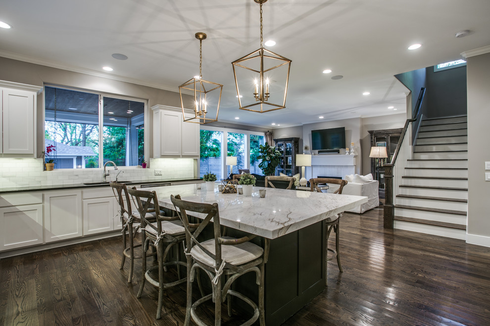 Photo of a large contemporary u-shaped open plan kitchen in Dallas with a built-in sink, shaker cabinets, white cabinets, engineered stone countertops, white splashback, limestone splashback, stainless steel appliances, medium hardwood flooring, brown floors, black worktops and an island.