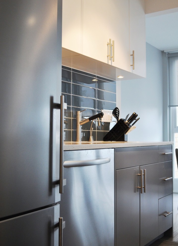 Zweizeilige Moderne Wohnküche mit Unterbauwaschbecken, flächenbündigen Schrankfronten, grauen Schränken, Quarzwerkstein-Arbeitsplatte, Küchenrückwand in Blau, Glasrückwand und Küchengeräten aus Edelstahl in Vancouver