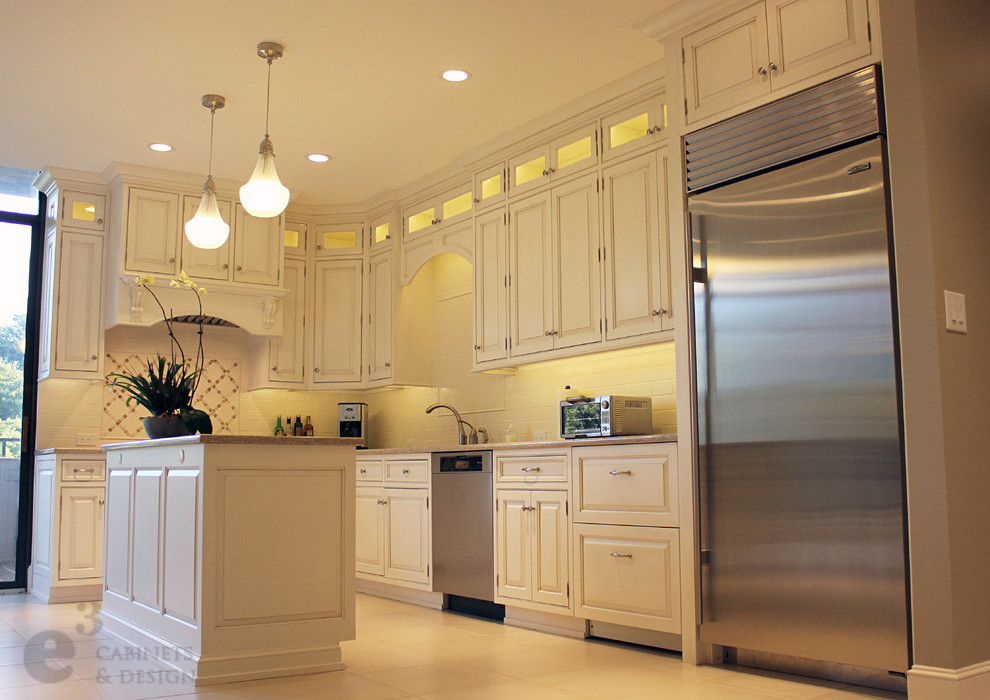 Inredning av ett klassiskt kök, med en undermonterad diskho, luckor med upphöjd panel, vita skåp, bänkskiva i kvarts, vitt stänkskydd, stänkskydd i tunnelbanekakel och rostfria vitvaror