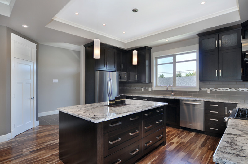Mid-sized trendy u-shaped medium tone wood floor open concept kitchen photo in Calgary with an undermount sink, shaker cabinets, dark wood cabinets, granite countertops, gray backsplash, ceramic backsplash, stainless steel appliances and an island