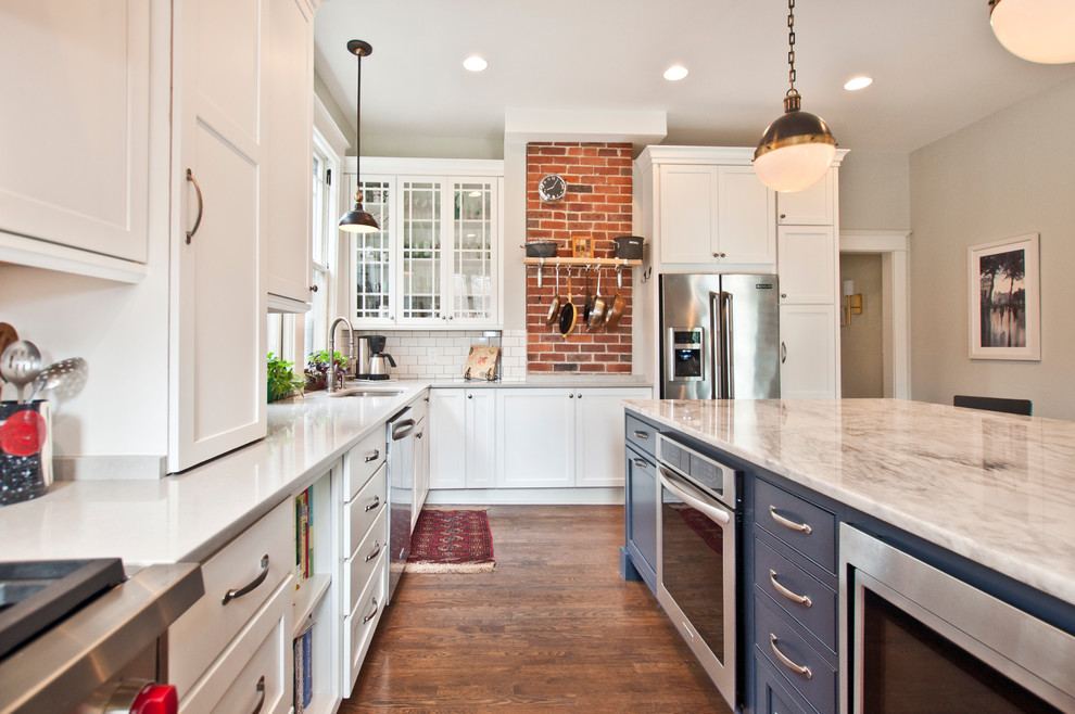 Eat-in kitchen - large transitional l-shaped medium tone wood floor and brown floor eat-in kitchen idea in Nashville with an undermount sink, shaker cabinets, white cabinets, marble countertops, white backsplash, porcelain backsplash, stainless steel appliances, an island and multicolored countertops