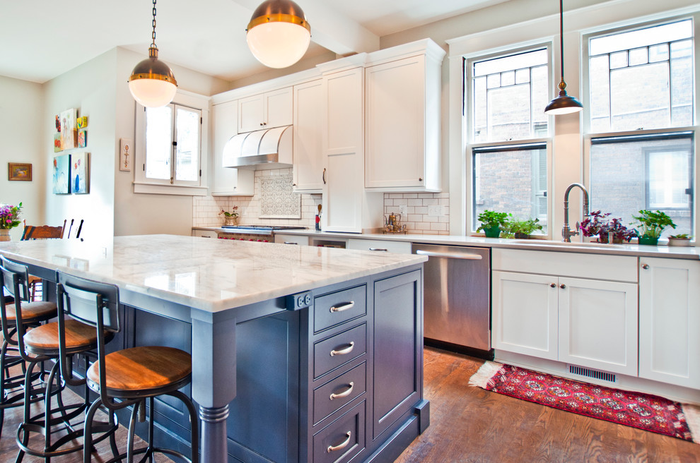 Inspiration for a large transitional l-shaped medium tone wood floor and brown floor eat-in kitchen remodel in Nashville with an undermount sink, shaker cabinets, white cabinets, marble countertops, white backsplash, porcelain backsplash, stainless steel appliances, an island and multicolored countertops