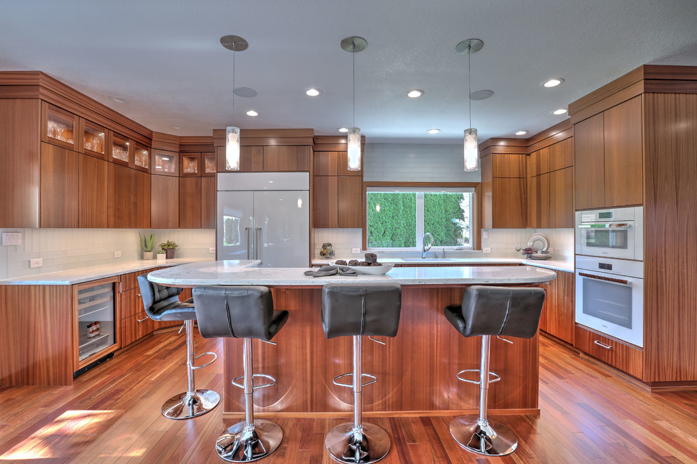 Open concept kitchen - large modern u-shaped medium tone wood floor and brown floor open concept kitchen idea in Seattle with an undermount sink, flat-panel cabinets, medium tone wood cabinets, laminate countertops, white backsplash, subway tile backsplash, white appliances and an island