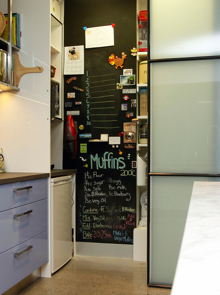 Geschlossene, Zweizeilige, Kleine Industrial Küche mit offenen Schränken, weißen Elektrogeräten und Betonboden in Melbourne