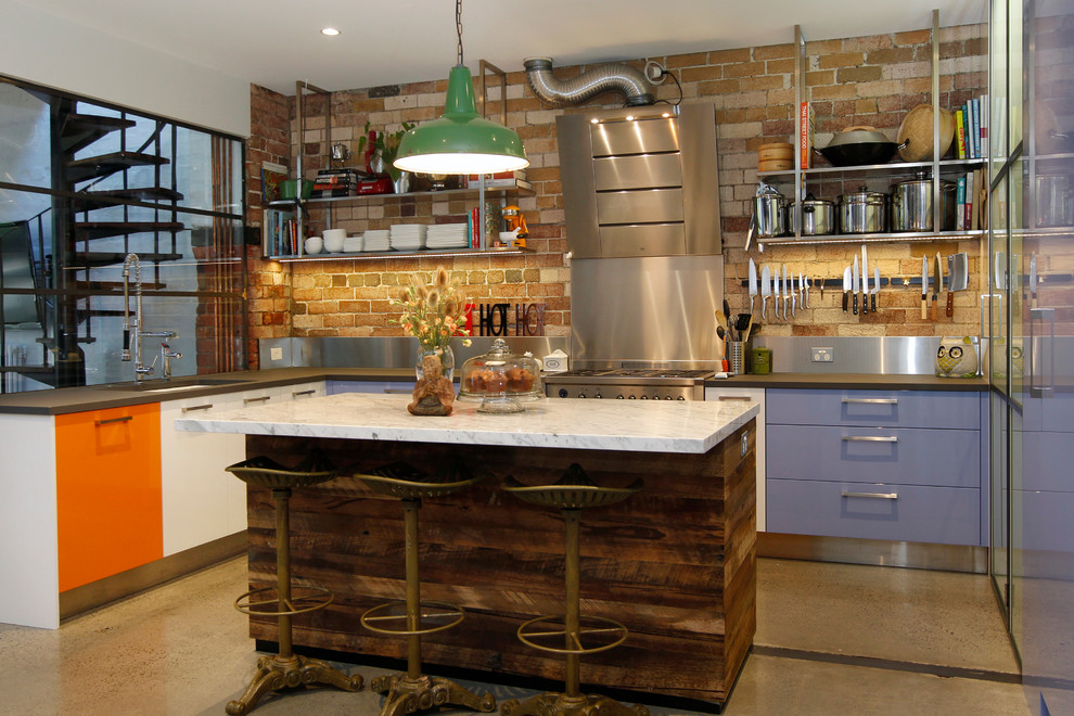 Mid-sized urban l-shaped concrete floor enclosed kitchen photo in Melbourne with an undermount sink, flat-panel cabinets, marble countertops, stainless steel appliances, an island and metallic backsplash