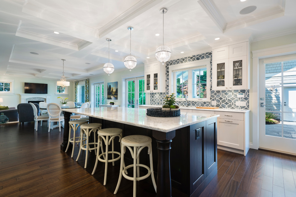 Large classic single-wall open plan kitchen in Vancouver with shaker cabinets, white cabinets, grey splashback, dark hardwood flooring and an island.