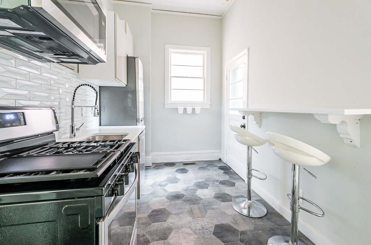 Exempel på ett litet modernt kök, med en undermonterad diskho, släta luckor, vita skåp, bänkskiva i kvarts, vitt stänkskydd, stänkskydd i keramik, rostfria vitvaror, cementgolv och grått golv