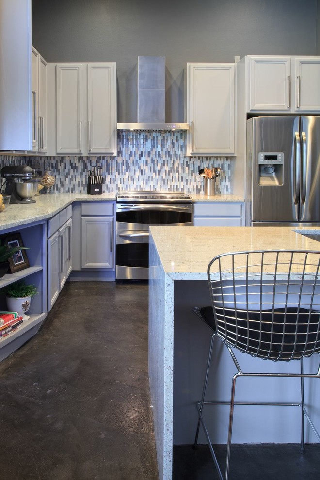 Modern inredning av ett mellanstort kök, med en undermonterad diskho, luckor med infälld panel, grå skåp, granitbänkskiva, vitt stänkskydd, stänkskydd i mosaik, rostfria vitvaror, betonggolv och en köksö