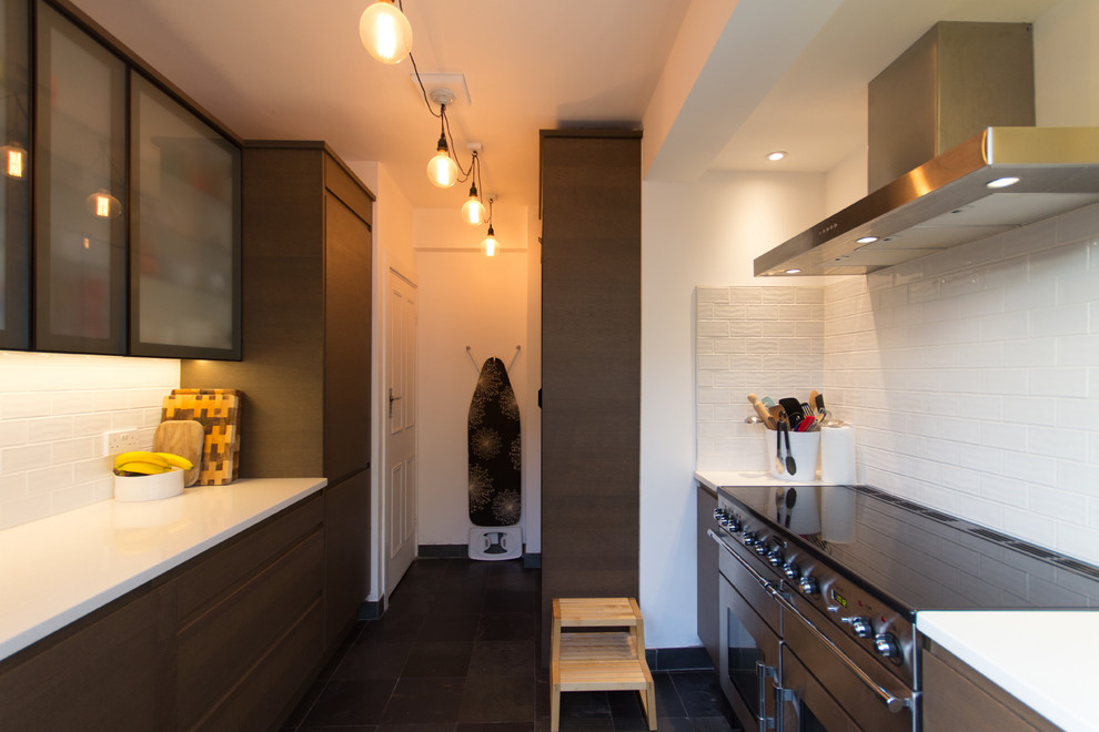Small contemporary u-shaped enclosed kitchen in London with an integrated sink, glass-front cabinets, brown cabinets, quartz worktops, white splashback, ceramic splashback, stainless steel appliances, slate flooring and no island.
