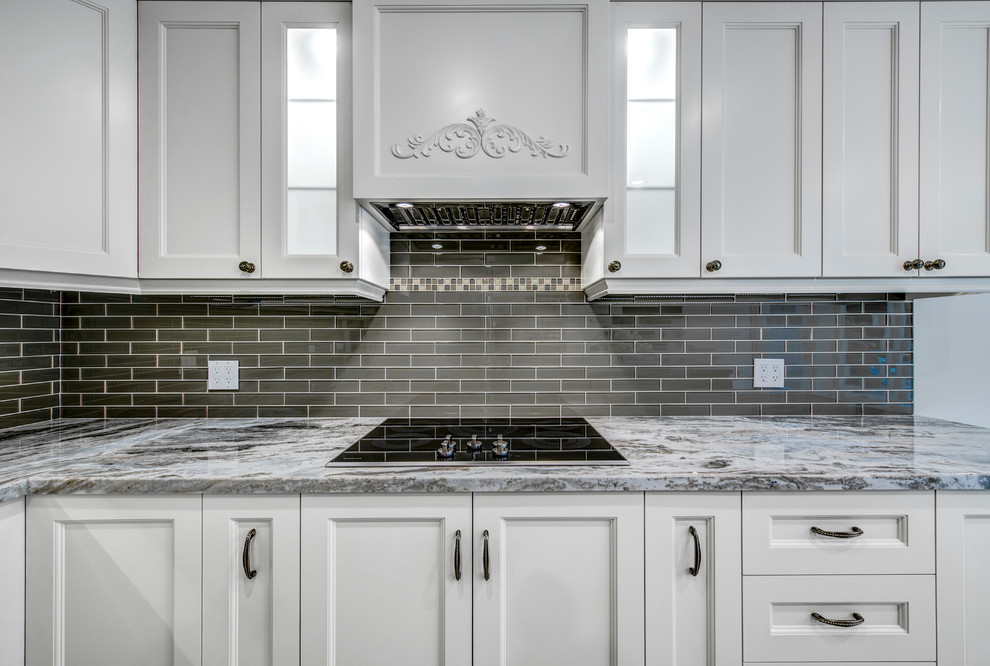 This is an example of a large contemporary u-shaped kitchen in Toronto with a submerged sink, shaker cabinets, grey cabinets, granite worktops, black splashback, metro tiled splashback, stainless steel appliances, an island and beige floors.