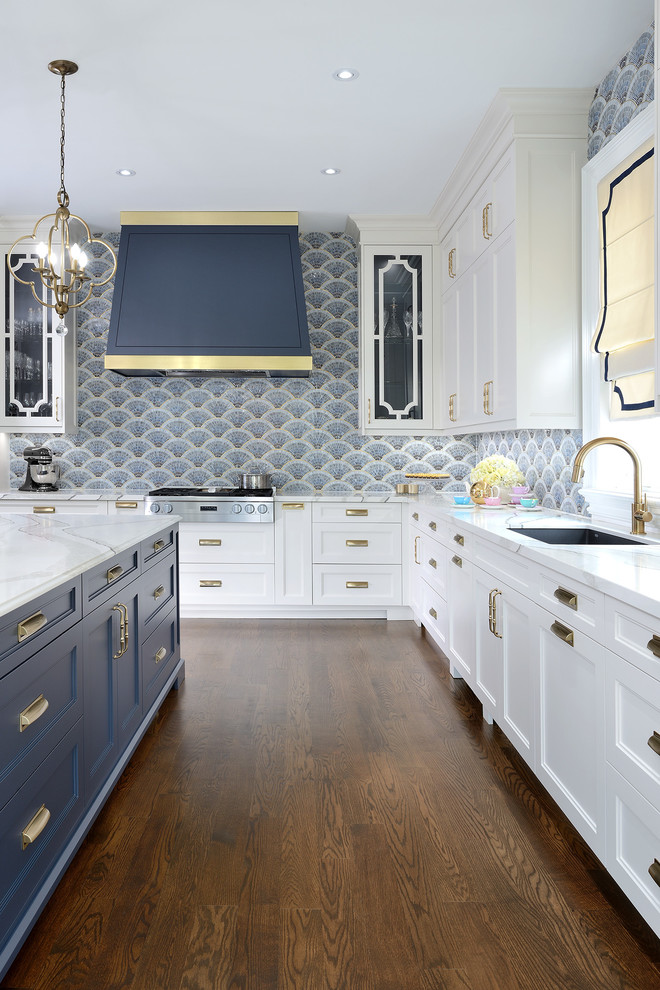 Exempel på ett stort klassiskt vit vitt kök, med en undermonterad diskho, luckor med infälld panel, vita skåp, bänkskiva i kvarts, blått stänkskydd, stänkskydd i mosaik, rostfria vitvaror, mellanmörkt trägolv, en köksö och brunt golv