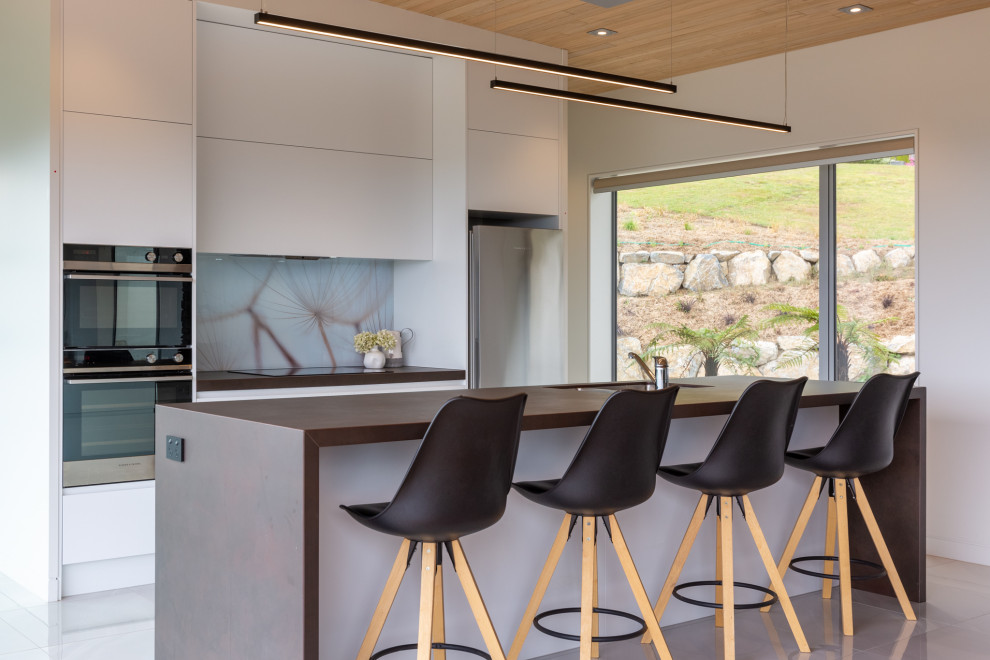 Immagine di una cucina contemporanea con lavello sottopiano, ante lisce, ante grigie, elettrodomestici in acciaio inossidabile, pavimento grigio e top grigio