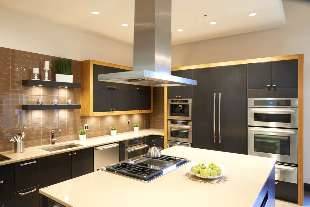 Medium sized modern l-shaped kitchen in Vancouver with a submerged sink, flat-panel cabinets, dark wood cabinets, engineered stone countertops, brown splashback, glass tiled splashback, stainless steel appliances and an island.