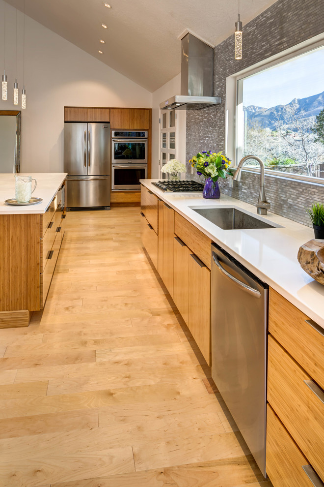 Inspiration for a mid-sized modern galley light wood floor eat-in kitchen remodel in Salt Lake City with an undermount sink, flat-panel cabinets, light wood cabinets, quartz countertops, gray backsplash, glass tile backsplash, stainless steel appliances and an island