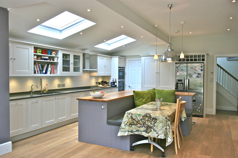 Example of a large trendy eat-in kitchen design in London with shaker cabinets, beige cabinets, wood countertops and an island