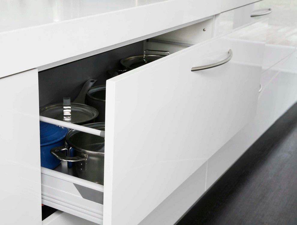 Design ideas for a large modern galley kitchen/diner in London with a submerged sink, flat-panel cabinets, white cabinets, composite countertops, white splashback, glass sheet splashback, stainless steel appliances, dark hardwood flooring and an island.